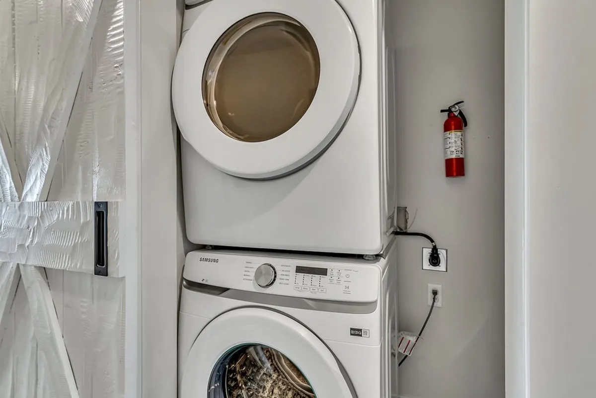 Functional laundry area with a stacked washer and dryer, a decorative barn door, and practical storage space. The scene is bright and efficient, ensuring household tasks are easy to manage.