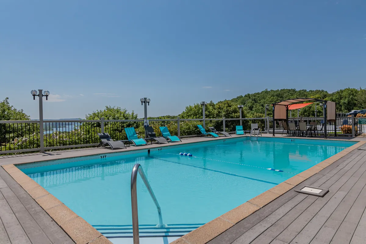 A serene outdoor swimming pool surrounded by lounge chairs and greenery. The pool area exudes relaxation and offers a tranquil space for guests to unwind, with views that hint at the surrounding landscape and communal areas for gatherings.