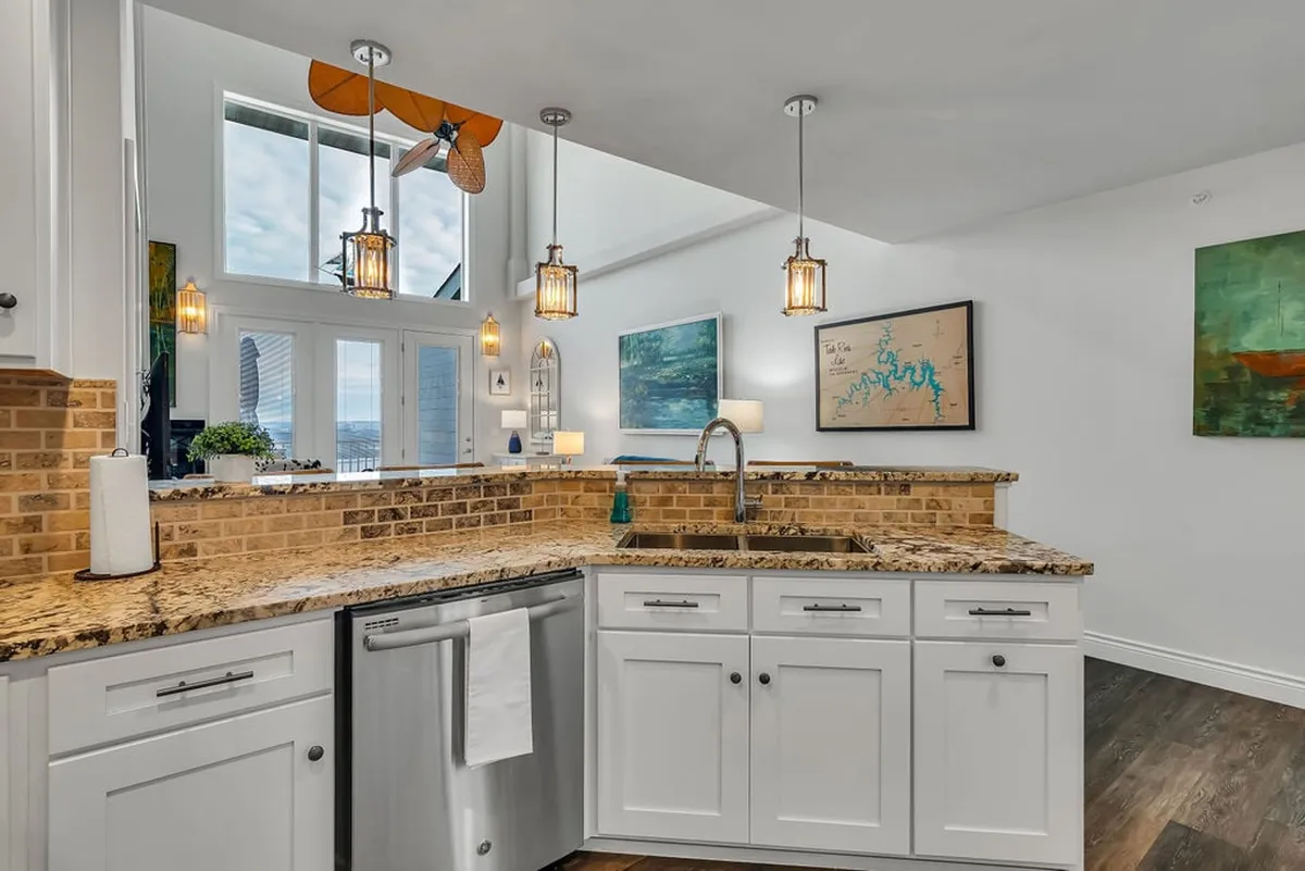This kitchen scene showcases elegant granite countertops paired with pendant lighting, a framed artwork, and a well-appointed kitchen sink. The inviting setup is designed for both entertaining and day-to-day family gatherings, blending style with practicality.
