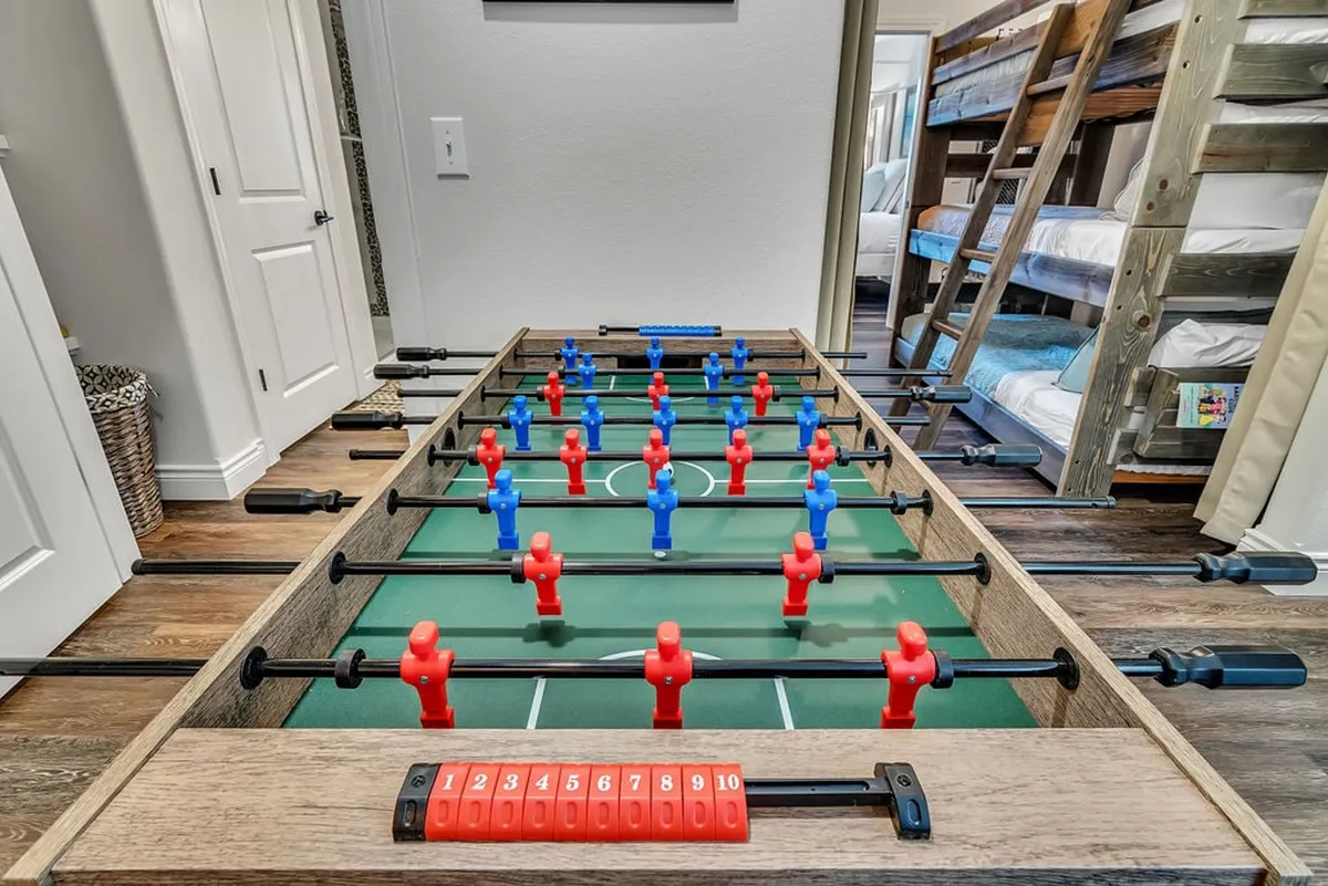 This energetic space features a foosball table, bunk beds, and decorative wall art, all set in a lively and youthful environment. It highlights the triple twin bunk alcove and play areas ideal for sleepovers and friendly competitions.